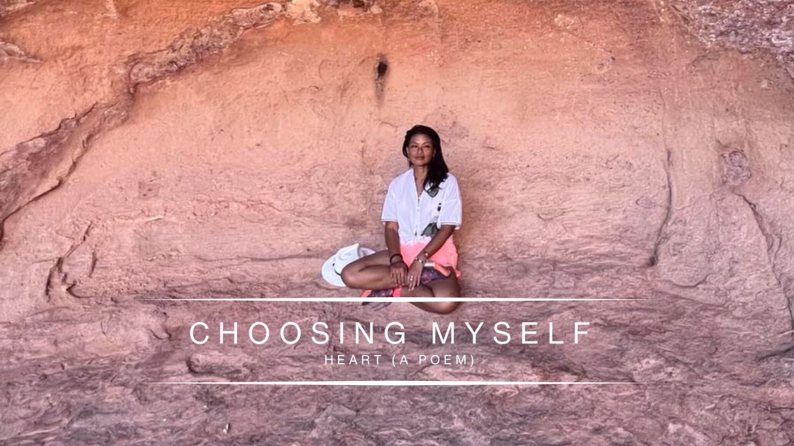 Genevieve Cheung sitting calmly against a natural rock wall, centered and grounded, reflecting on choosing herself, grief, and inner clarity.