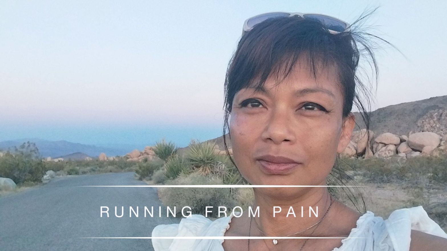 Portrait of Genevieve Cheung standing outdoors on a quiet desert road at dusk, reflecting on transition and emotional healing.